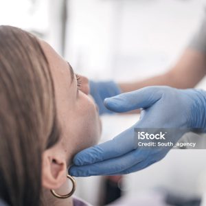 Arzt tastet den Kiefer einer Patientin